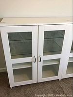 White cabinet with two doors and glass panels, showing exterior closed view.