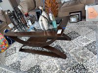 Full view of espresso coffee table showing glass top, curved legs, and lower shelf with various decorative items on top but not included.