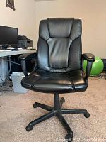 Front view of black faux leather office chair showing padded seat and backrest with small tear on lower front seat.
