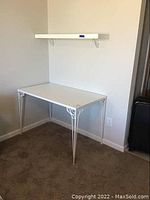 White MFC corner desk with decorative metal legs seen assembled on carpeted floor near wall corner.