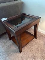 End table upright showing glass inset top and thick wooden frame