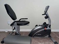 Side view of the full recumbent exercise bike showing padded backrest, seat, and console.