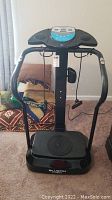 Full front view of the Bluefin Pro vibration plate with resistance cords and curved handles on a carpeted floor.