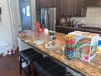 Wide view of kitchen counter displaying various glassware and dinnerware including glasses, mugs, plates, and glass containers