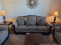 Pair of espresso metal table lamps on brown end tables flanking a beige sofa in a living room setting.