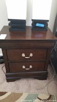 Pair of nightstands shown side by side with 2 drawers each and table lamps on top