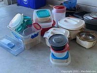 Plastic storage containers and serving pieces arranged on the floor, showcasing variety of sizes and lids.