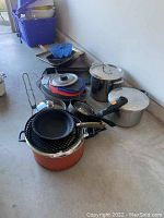 Photo of assorted pots, pans, woks, and bakeware showing condition and variety of items