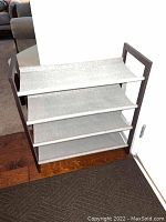 Front angle view of shoe rack showing 4 gray canvas shelves and espresso wood frame in foyer setting.