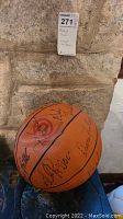 Close-up photo showing multiple signatures on the basketball with Atlanta Hawks logo visible.