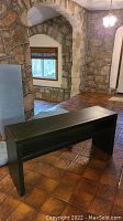 Photo of dark stained wood rectangular table in stone and tile room, showing table detail and condition.