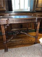 Front view of table showing carved lattice apron and bamboo-style turned legs