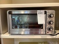Front view of the Cuisinart toaster oven showing chrome exterior, glass door, and inset control panel with three knobs.