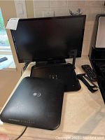 View of the TV screen with Antenna Direct device and remote control on the counter, showing size and included accessories