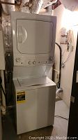Full front view of white GE stackable washer and dryer unit in utility room.