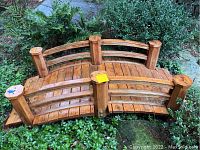 Arched wooden garden bridge placed among ground cover and foliage