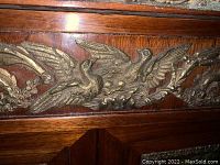 Close-up of brass appliqué showing two birds and foliage on wood trim