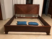 King size wooden bed frame assembled in room, showing headboard, footboard and side rails