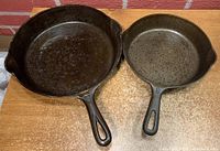 Two Griswold cast iron frying pans in sizes 6 and 9 viewed from above showing the cooking surfaces and pouring spouts on each side.