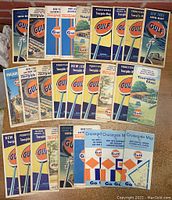 Collection of 27 folded vintage road maps from Gulf arranged in rows, showing variety of states including Pennsylvania, New Jersey, Ohio, and others. Colorful mid-century design with Gulf logo.