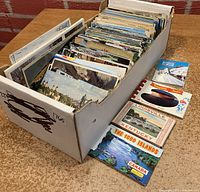 Box filled with assorted vintage postcards and a few small souvenir booklets placed in front of the box