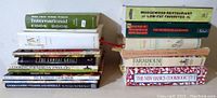 Two stacks of 14 cookbooks showing binding titles including International Cook Book and Moosewood Restaurant titles.