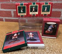 Four Hallmark Keepsake penguin ornaments boxed: 'Dapper Penguin' (1985), 'Icy Treat' (1987), 'Special Delivery' (1986), and 'Putt-Putt Penguin' (1993) plus two Hallmark ornament display stands boxed.