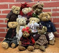 Full group photo of 9 Bearington Collection teddy bears in various styles and clothes, against brick wall background