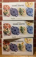 Three boxed sets of Martha Stewart Collector's Ceramic Cocottes, each box shows four different colored cocottes.
