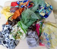 Collection of various vintage scarves in different colors and patterns laid out on a flat surface.