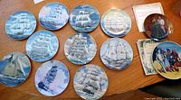Overview of all collector plates showing 12 sailing ship plates and 2 themed plates (Wizard of Oz and Gone With the Wind)