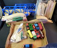 Lot overview showing several wooden train cars, blue and green bridges, and curved wooden railway tracks in bundles.