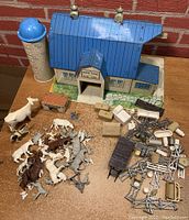 Full lot showing vintage Marx farm barn with silo, a variety of plastic and metal farm animals, and numerous farm accessories including fences and barrels.