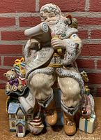 Front view of Georgian Santa Claus cookie jar holding a list with toys at the base.