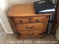 Photo of a birch wood end table showing three drawers, metal handles, and wood grain finish.