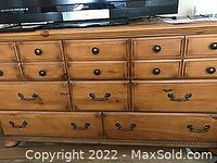 Front view of large birch dresser with eight drawers with various wooden and metal handles, no mirror attached.