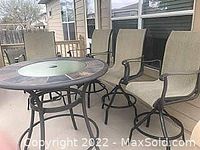Round patio table with mosaic tile border and glass center, four beige mesh swivel chairs around it