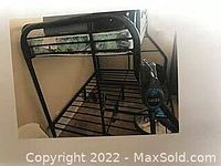 Steel tubular bunk beds with black frame, bottom full size mattress and top twin size mattress. The frame has side supports and a ladder for the top bunk.