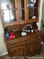Full view of the two piece hutch made of wood with glass doors on upper section and drawers and cabinet doors on the bottom section
