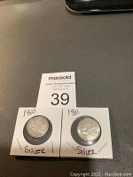 Front view of the two Canadian silver quarters dated 1960 and 1961 in white cardboard holders with MaxSold auction lot marker.