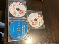 Three Wii game discs on dark surface: Mario Party 8, Wii Sports, Wii Play.