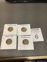 Four Canadian 1 cent penny coins from 1943 in individual white cardboard holders with handwritten dates.