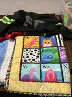Lot items arranged to show baby blankets and quilts with the black fireman coat on top