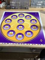 Full view of the large round sheet with 12 stamp cutouts on a workbench.