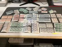 Overview of multiple blocks and sheets of mint Canadian postage stamps featuring Queen Elizabeth II in various colors and denominations arranged on black and white backgrounds