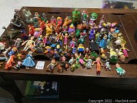 Overview of entire lot showing all figurines and toys grouped on table surface in loose arrangement.