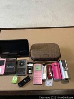 Overview of electronic items arranged on flat surface including calculators, portable speaker, USB drives, and digital devices.