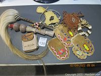 Overview of the lot showing medicine bag, leather wind catcher, moccasin covers, choker, African rattle, and medicine whip with various beadwork and natural materials.