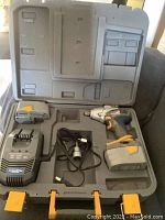 Full case open showing drill, two batteries, charger, power cord, and case interior.