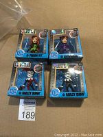 Four boxed DC Comics die-cast metal figures: Poison Ivy, Catwoman, and two Harley Quinns in different outfits.